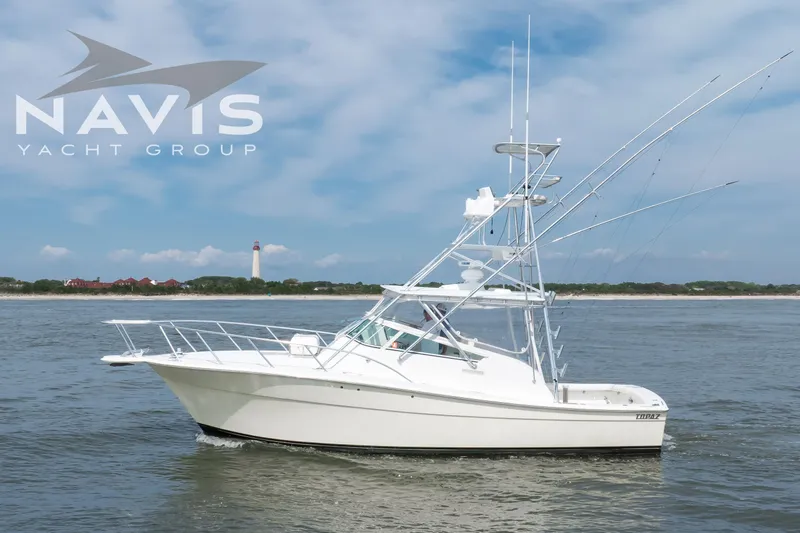 Pipe Dream Yacht Photos Pics 2005 Topaz 32 Express yacht cruising near a lighthouse, under a clear blue sky.