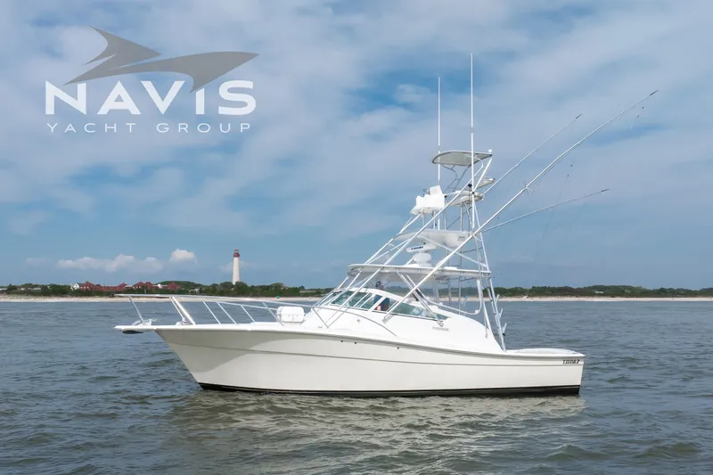 Pipe Dream Yacht Photos Pics 2005 Topaz 32 Express yacht on water, Navis Yacht Group logo, lighthouse in background.