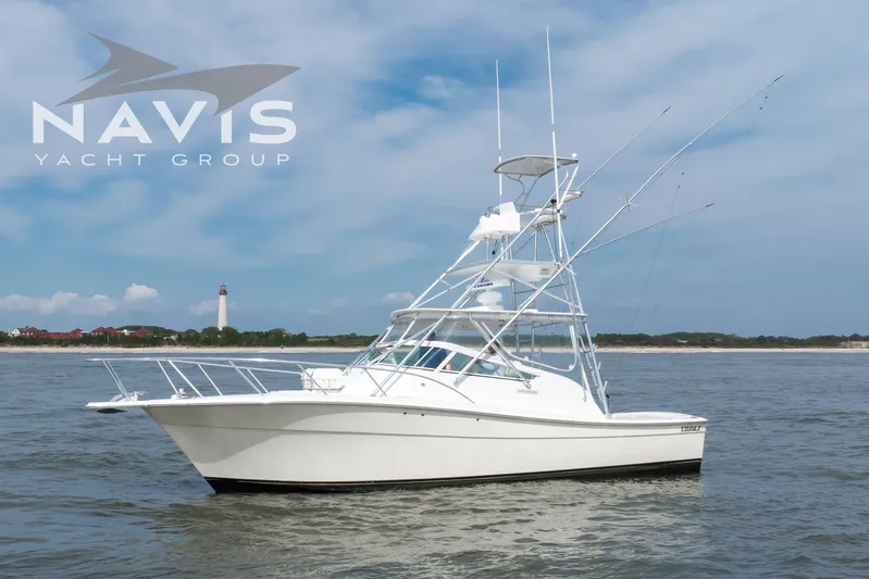 Pipe Dream Yacht Photos Pics 2005 Topaz 32 Express yacht on water, with lighthouse in background.