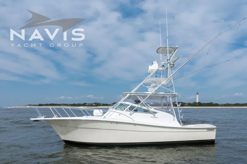 Pipe Dream Yacht Photos Pics 2005 Topaz 32 Express yacht on water, blue sky, lighthouse in background.