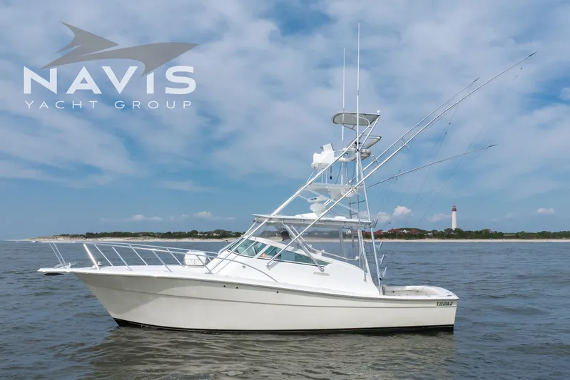 Pipe Dream Yacht Photos Pics 2005 Topaz 32 Express yacht on water, Navis Yacht Group logo, lighthouse in background.