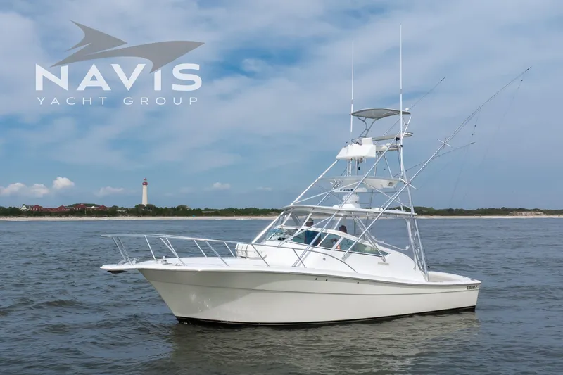 Pipe Dream Yacht Photos Pics 2005 Topaz 32 Express yacht on water, Navis Yacht Group logo, lighthouse in background.