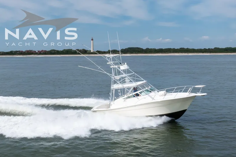 Pipe Dream Yacht Photos Pics 2005 Topaz 32 Express yacht cruising near a lighthouse, Navis Yacht Group logo visible.