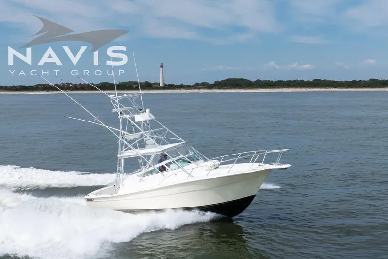 Pipe Dream Yacht Photos Pics 2005 Topaz 32 Express yacht cruising near a lighthouse, Navis Yacht Group logo visible.