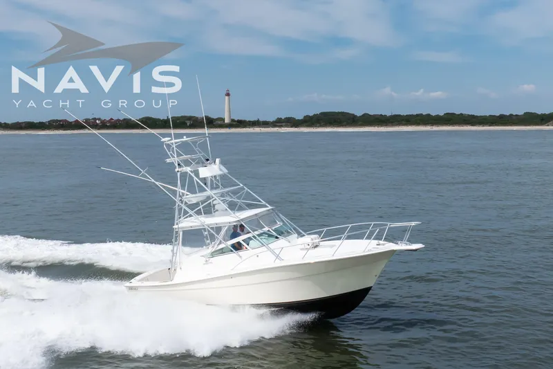 Pipe Dream Yacht Photos Pics 2005 Topaz 32 Express yacht cruising near a lighthouse, Navis Yacht Group logo visible.