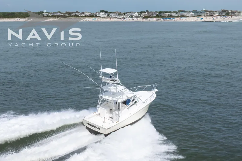 Pipe Dream Yacht Photos Pics 2005 Topaz 32 Express yacht cruising near a beach, Navis Yacht Group logo visible.