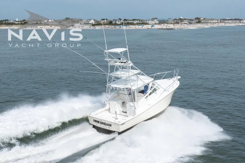 Pipe Dream Yacht Photos Pics 2005 Topaz 32 Express yacht cruising near a coastal town.