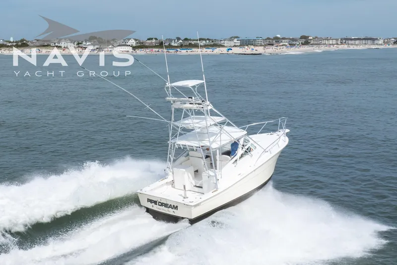 Pipe Dream Yacht Photos Pics 2005 Topaz 32 Express yacht cruising near a beach, Navis Yacht Group branding visible.