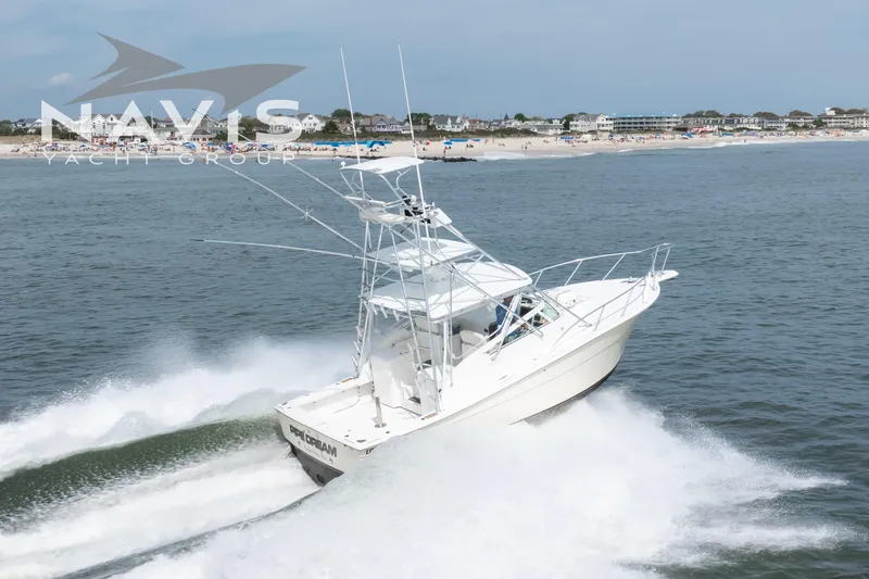 Pipe Dream Yacht Photos Pics 2005 Topaz 32 Express yacht cruising near a busy beach shoreline.