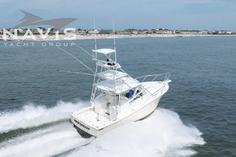 Pipe Dream Yacht Photos Pics 2005 Topaz 32 Express yacht cruising on open water near a coastal town.