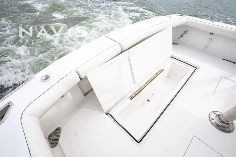 Pipe Dream Yacht Photos Pics 2005 Topaz 32 Express yacht deck with open storage compartment, white seating, and ocean backdrop.