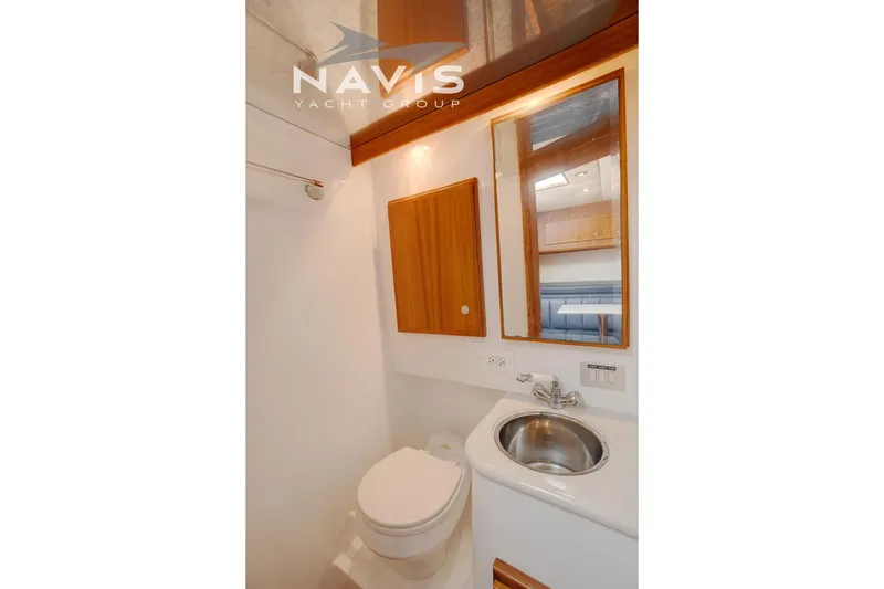 Pipe Dream Yacht Photos Pics 2005 Topaz 32 Express yacht bathroom with sink, toilet, and wooden cabinetry.