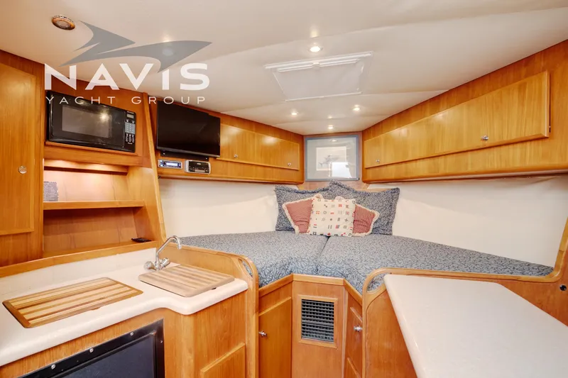 Pipe Dream Yacht Photos Pics Interior of 2005 Topaz 32 Express yacht with cozy bed, microwave, and wooden cabinetry.