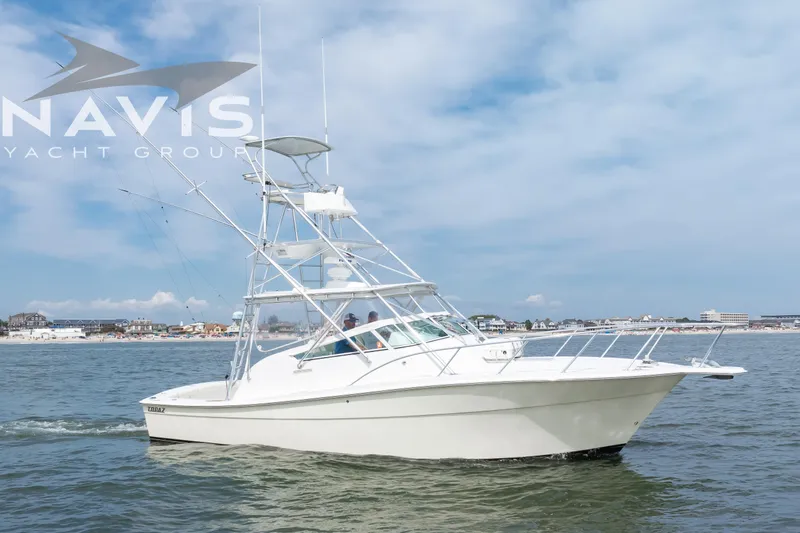 Pipe Dream Yacht Photos Pics 2005 Topaz 32 Express yacht cruising on calm waters near a coastal town.