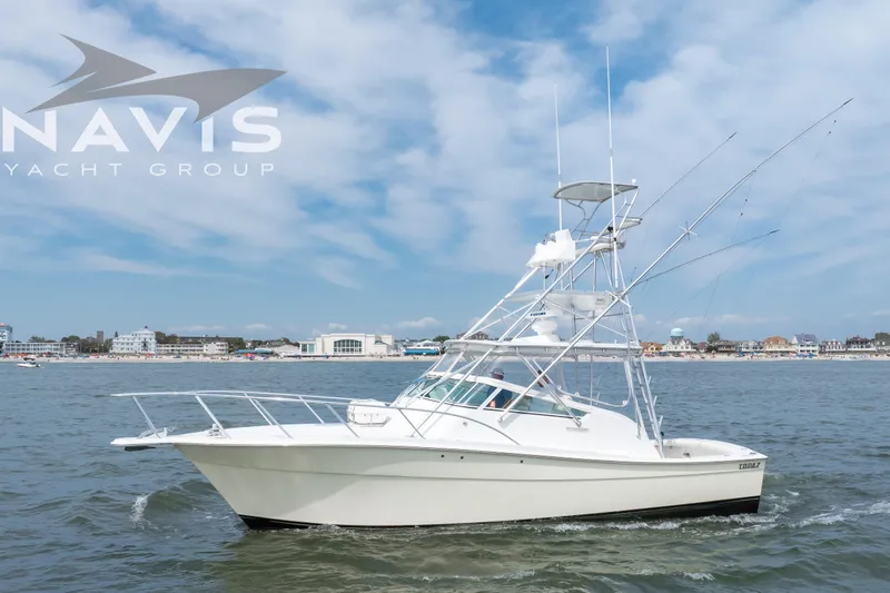 Pipe Dream Yacht Photos Pics 2005 Topaz 32 Express yacht cruising near coastal town under blue sky.