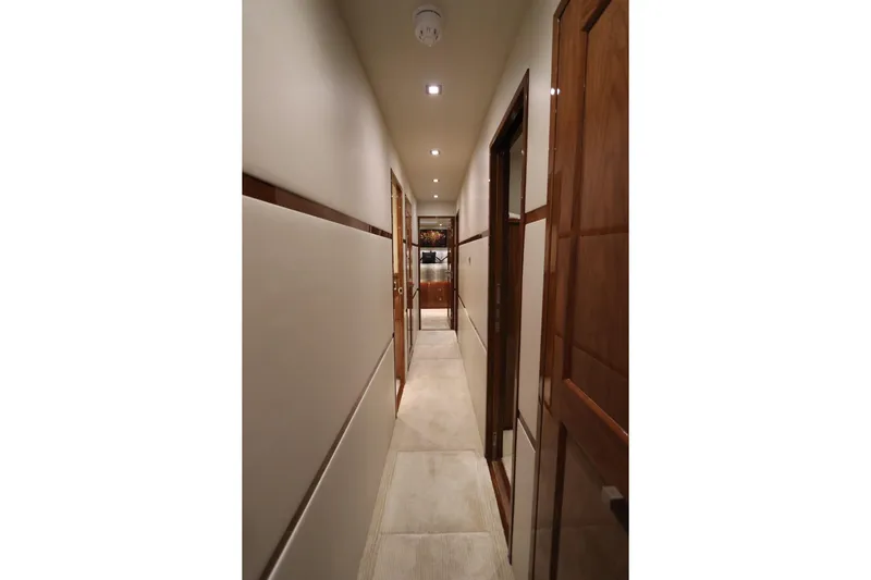 Stress Release Yacht Photos Pics Hallway inside 2017 Viking 80 Enclosed Bridge yacht, featuring elegant wood paneling and modern lighting.