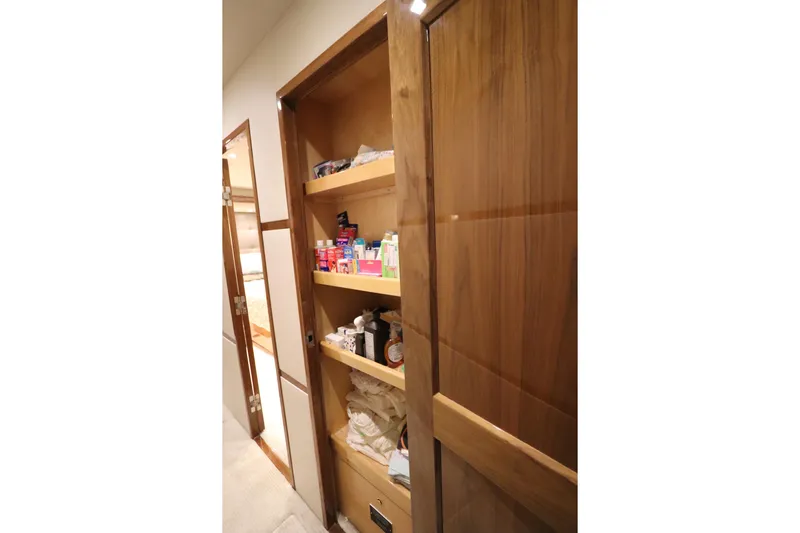 Stress Release Yacht Photos Pics Wooden storage shelves inside a 2017 Viking 80 Enclosed Bridge yacht, stocked with various items.