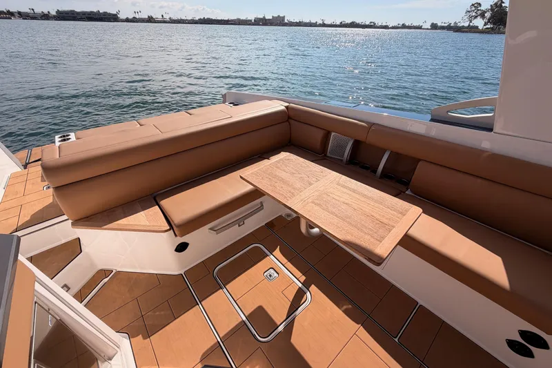 Wonder Why Yacht Photos Pics 2022 Aviara AV32 I/O boat interior with tan seating and wooden table, overlooking serene water.