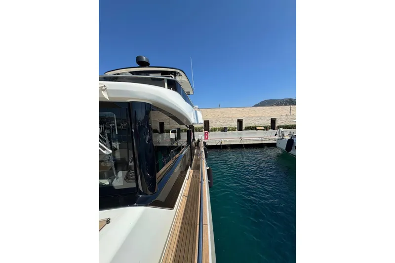  Yacht Photos Pics 2022 Cranchi T55 Trawler docked at marina, clear blue sky, and calm water.