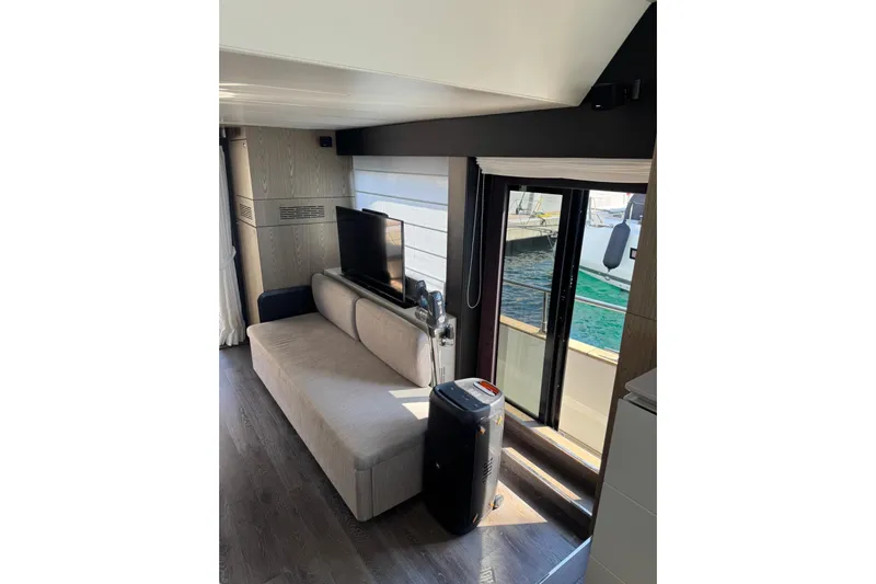  Yacht Photos Pics Interior of 2022 Cranchi T55 Trawler with sofa, TV, and sliding door to deck.