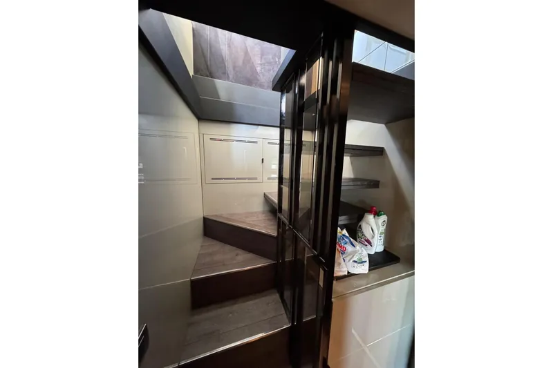 Yacht Photos Pics Interior staircase of 2022 Cranchi T55 Trawler yacht, featuring modern design and storage shelves.