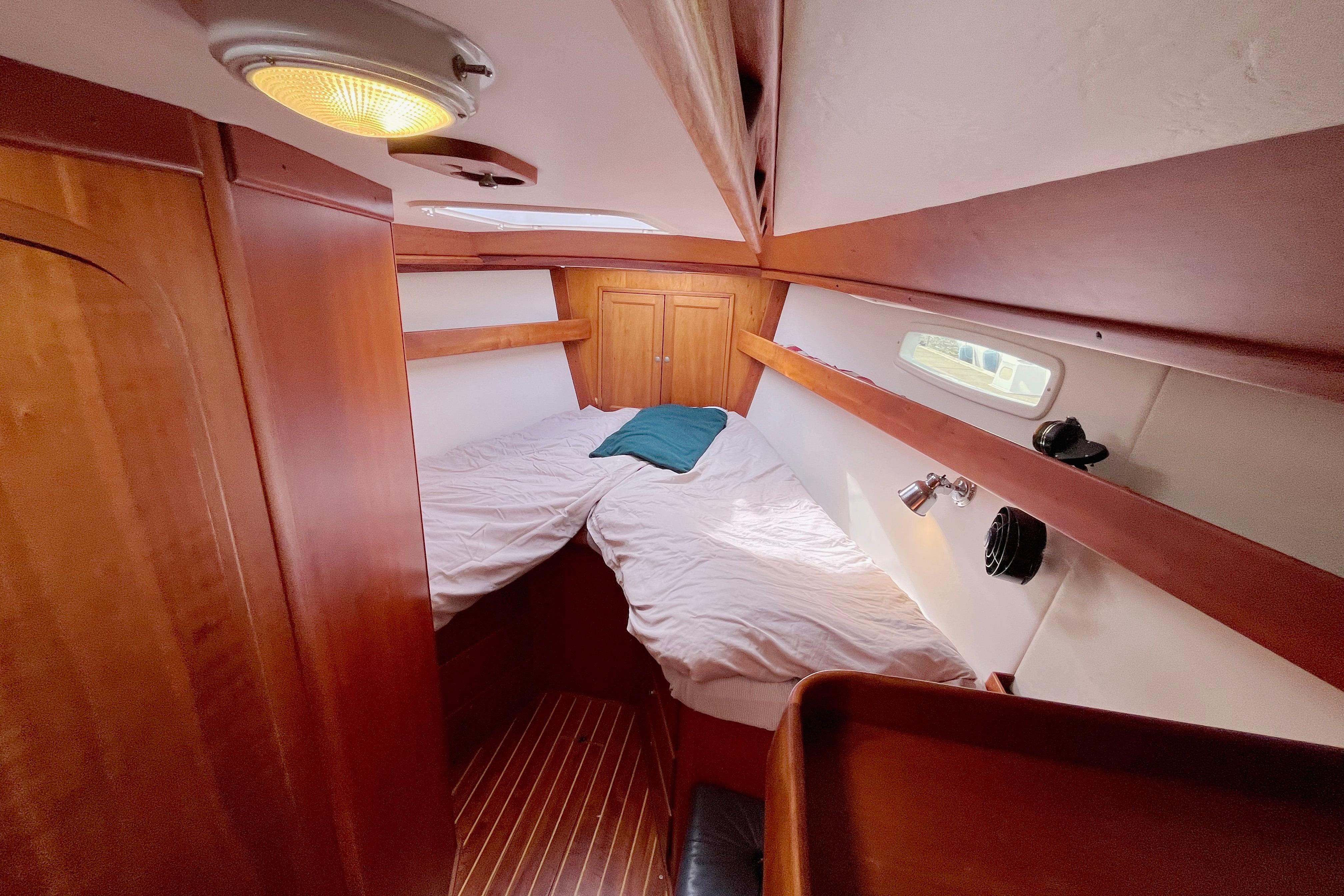 Cozy cabin interior of 1995 Able Apogee 50 sailboat with wooden finishes and bedding.
