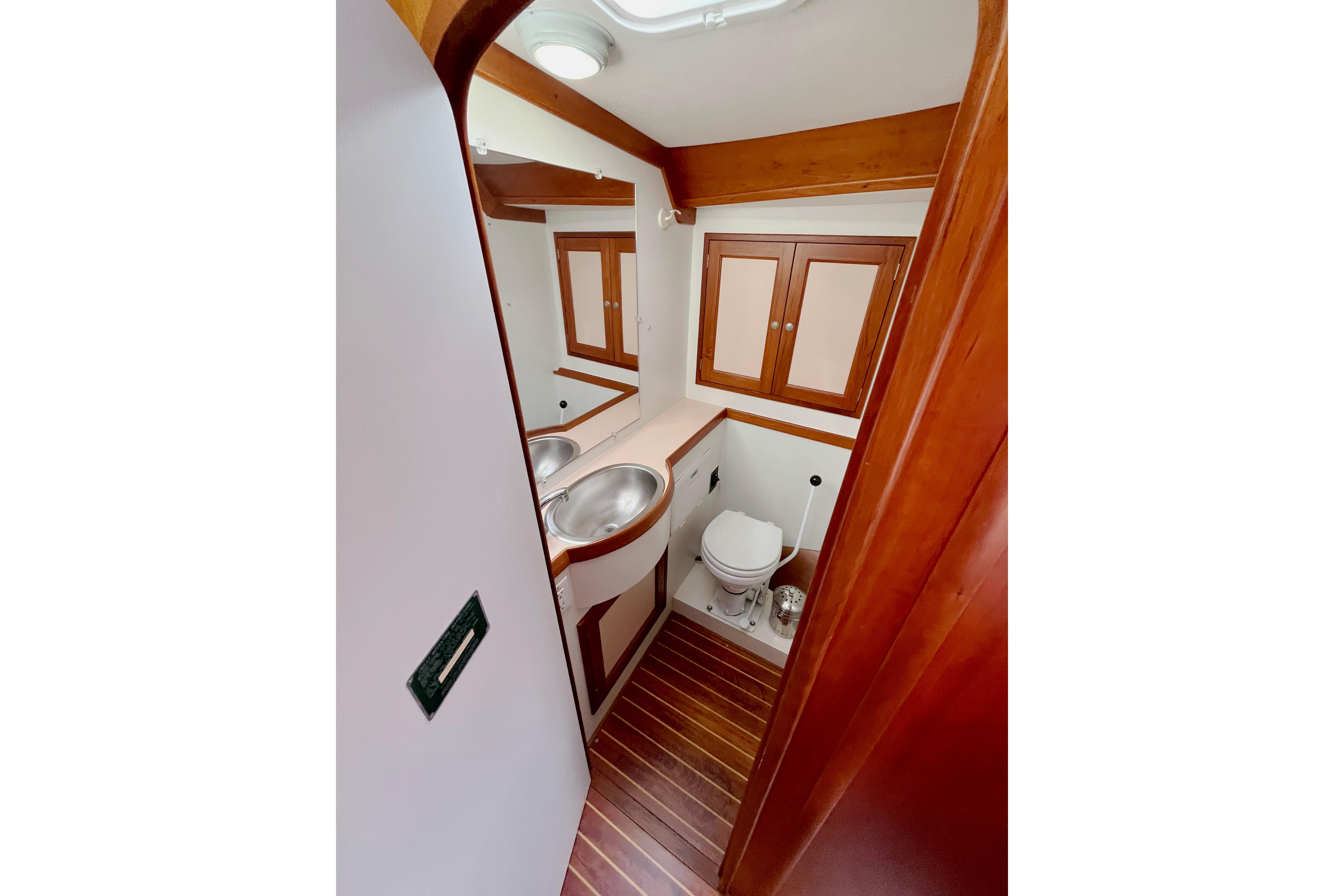 1995 Able Apogee 50 yacht bathroom with wooden cabinetry and stainless steel sink.
