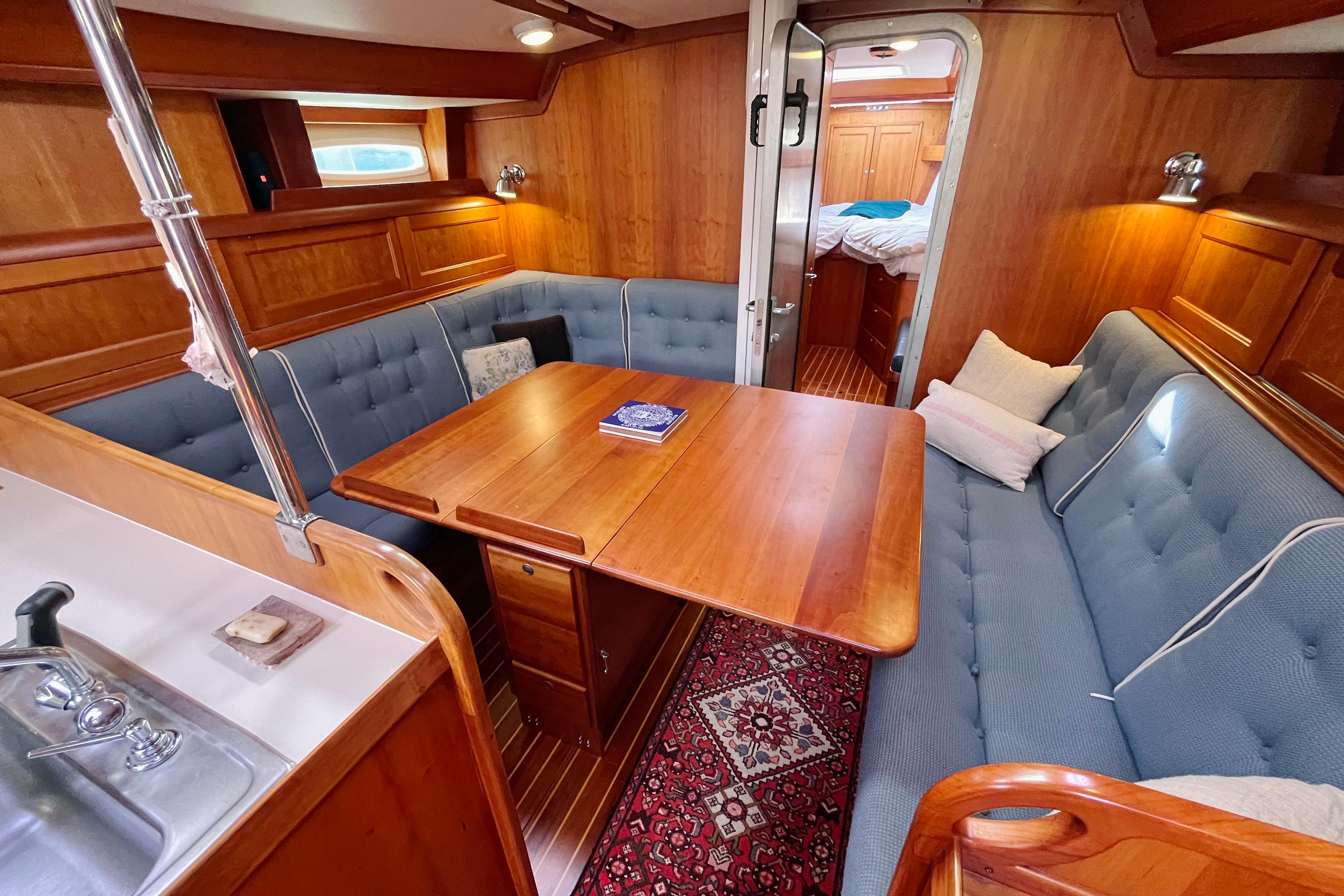 Luxurious 1995 Able Apogee 50 yacht interior with wooden dining area and blue seating.