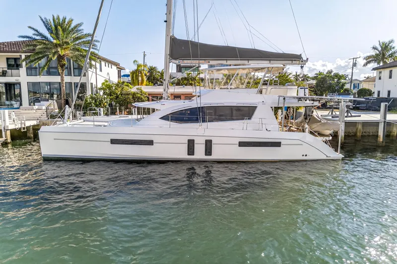  Yacht Photos Pics 2019 Leopard 58 catamaran docked by waterfront homes, showcasing sleek design and modern features.
