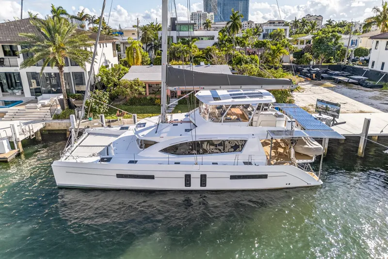  Yacht Photos Pics 2019 Leopard 58 catamaran docked in a sunny marina, surrounded by lush greenery.