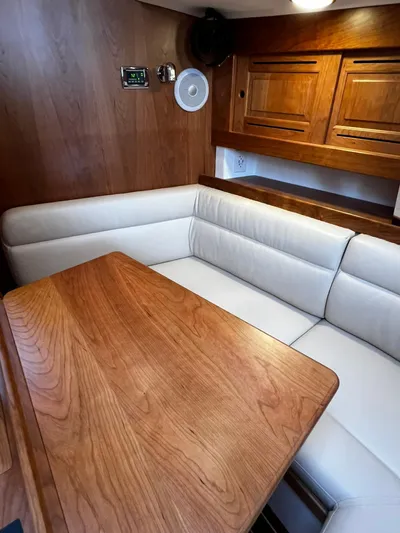 395 Yacht Photos Pics 2025 Tartan 395 yacht interior with wooden table and white cushioned seating.