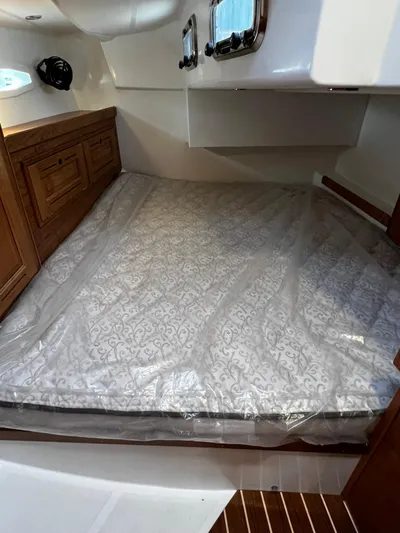 395 Yacht Photos Pics 2025 Tartan 395 cabin interior with bed, wooden cabinetry, and portholes.