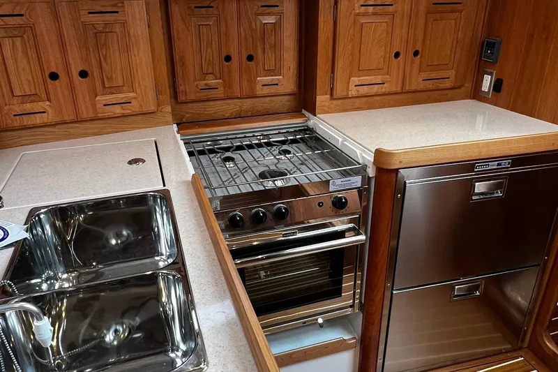 395 Yacht Photos Pics Modern kitchen in 2025 Tartan 395 yacht with stove, sink, and wooden cabinetry.