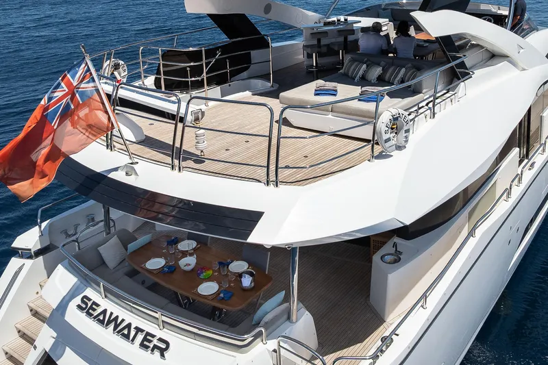 Seawater Yacht Photos Pics Sunseeker 86 Yacht 2019, luxurious deck with seating and dining area, ocean backdrop.