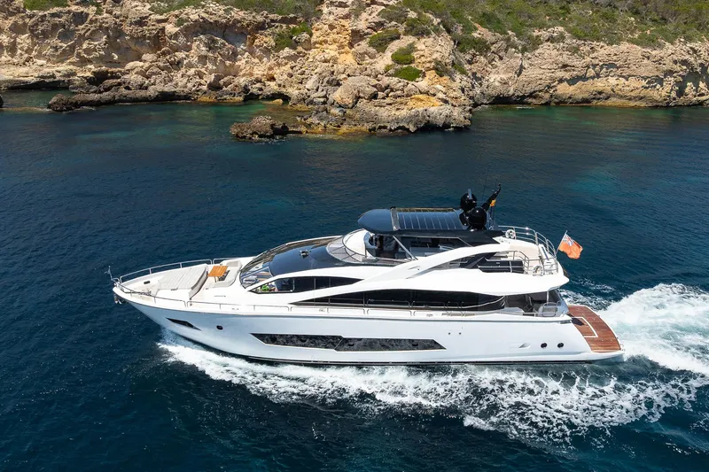 Seawater Yacht Photos Pics 2019 Sunseeker 86 Yacht cruising near rocky coastline in clear blue waters.
