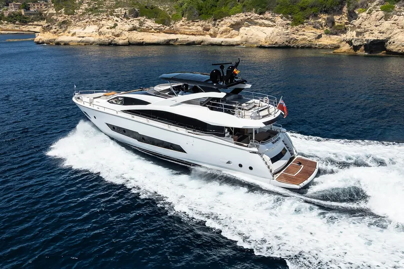 Seawater Yacht Photos Pics 2019 Sunseeker 86 Yacht cruising in clear blue waters near rocky coastline.