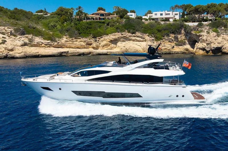 Seawater Yacht Photos Pics 2019 Sunseeker 86 Yacht cruising near rocky coastline under clear blue sky.