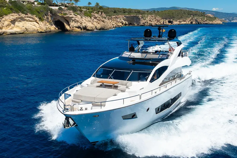Seawater Yacht Photos Pics 2019 Sunseeker 86 Yacht cruising on clear blue waters near rocky coastline.