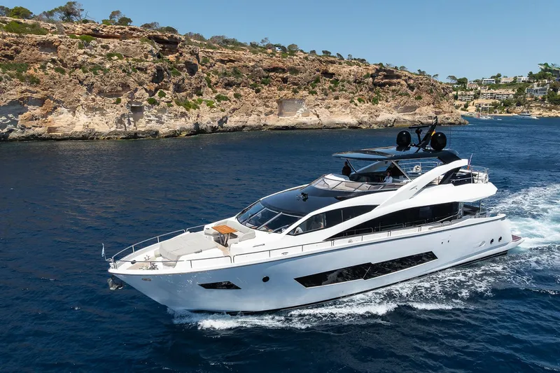 Seawater Yacht Photos Pics Luxurious 2019 Sunseeker 86 Yacht cruising near rocky coastline under clear blue sky.
