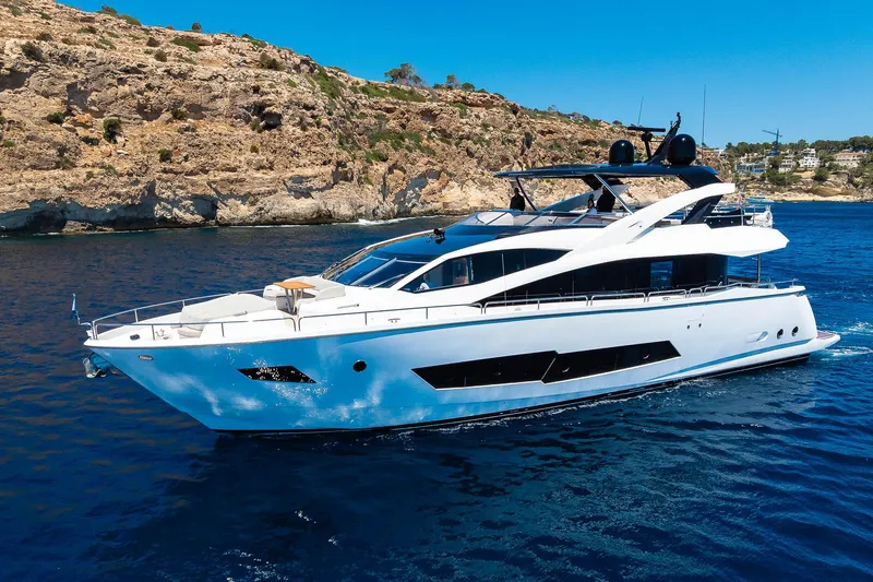 Seawater Yacht Photos Pics Luxurious 2019 Sunseeker 86 Yacht cruising in clear blue waters near rocky coastline.