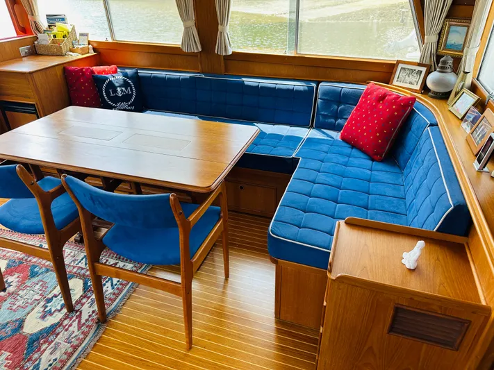 Sora Yacht Photos Pics Interior of 1998 Grand Banks 49 Classic with blue seating, wooden table, and red cushions.
