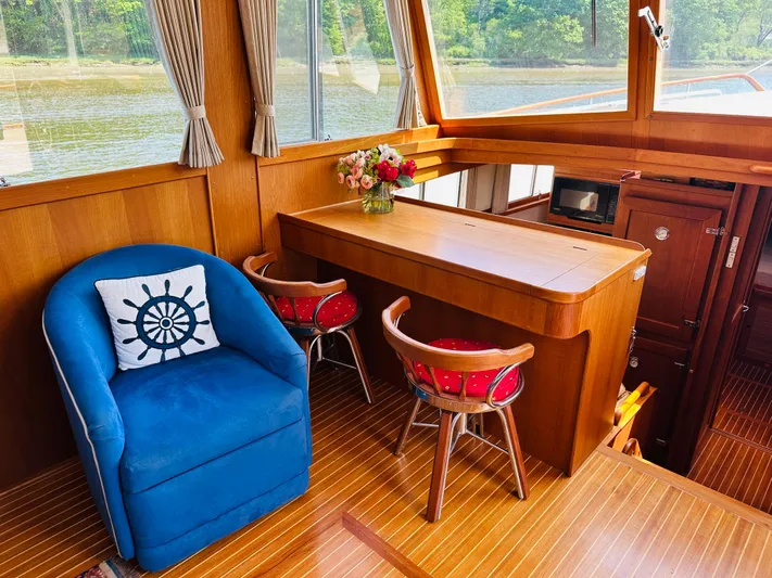 Sora Yacht Photos Pics Interior of 1998 Grand Banks 49 Classic yacht with blue chair and wooden table.