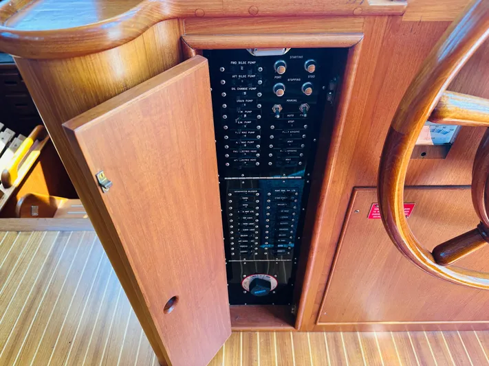 Sora Yacht Photos Pics Electrical panel inside a 1998 Grand Banks 49 Classic yacht, with wooden cabinetry and steering wheel.
