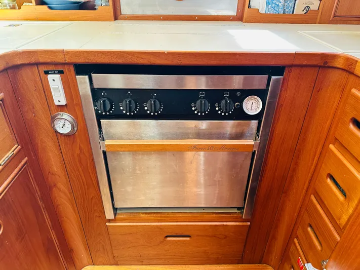 Sora Yacht Photos Pics Galley oven in 1998 Grand Banks 49 Classic yacht, featuring wooden cabinetry and control knobs.