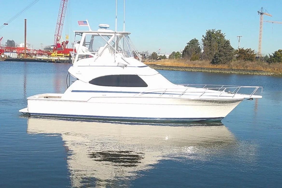 2005 Bertram 390 Convertible yacht on calm water, with industrial background.