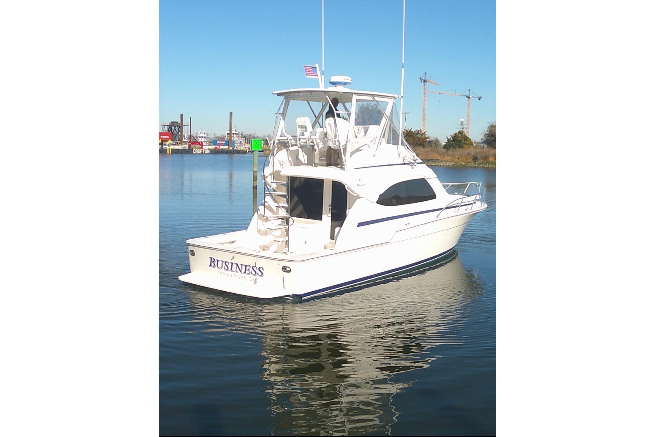 2005 Bertram 390 Convertible yacht on calm water, rear view with marina background.