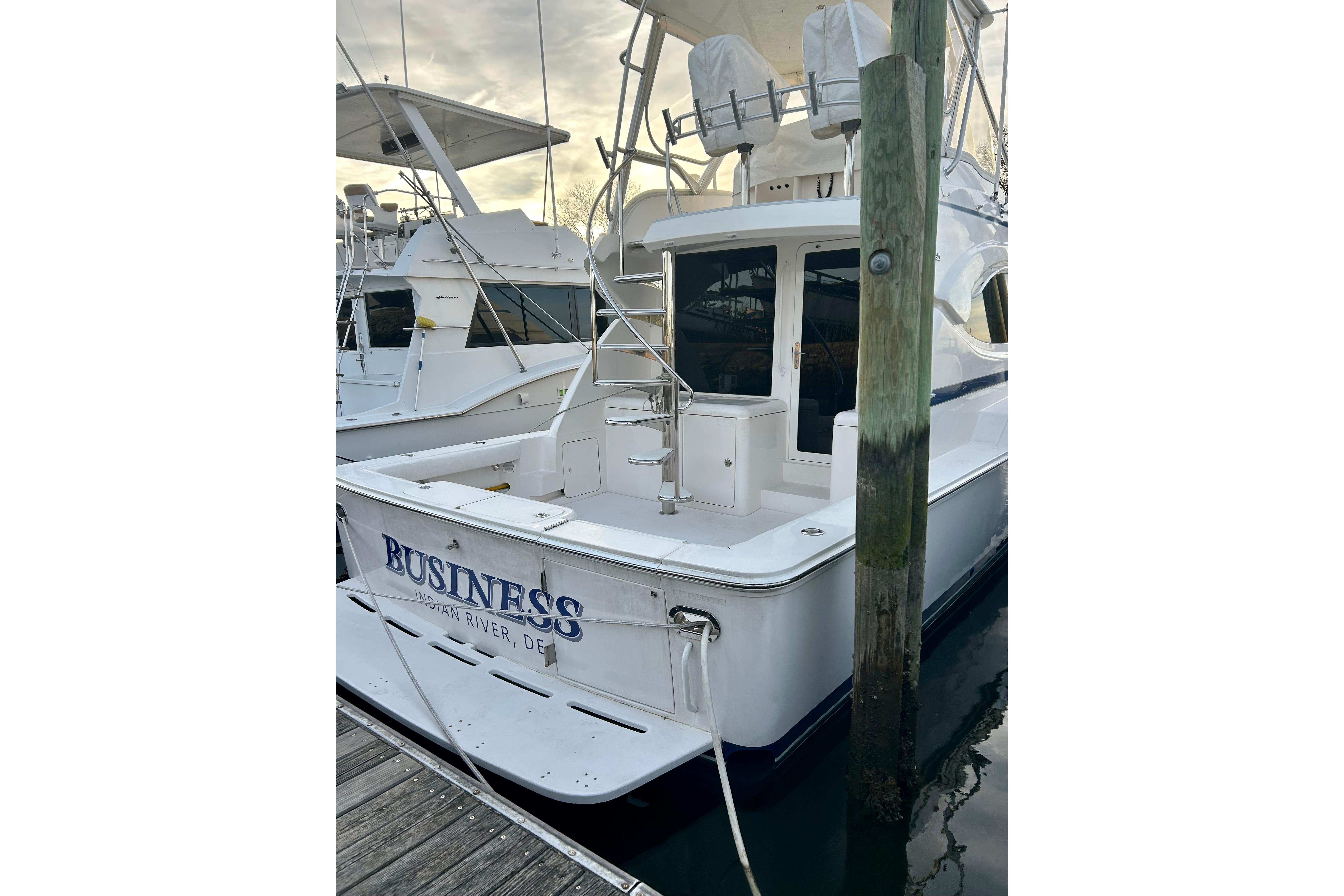 2005 Bertram 390 Convertible yacht docked, rear view with ladder and seating area.