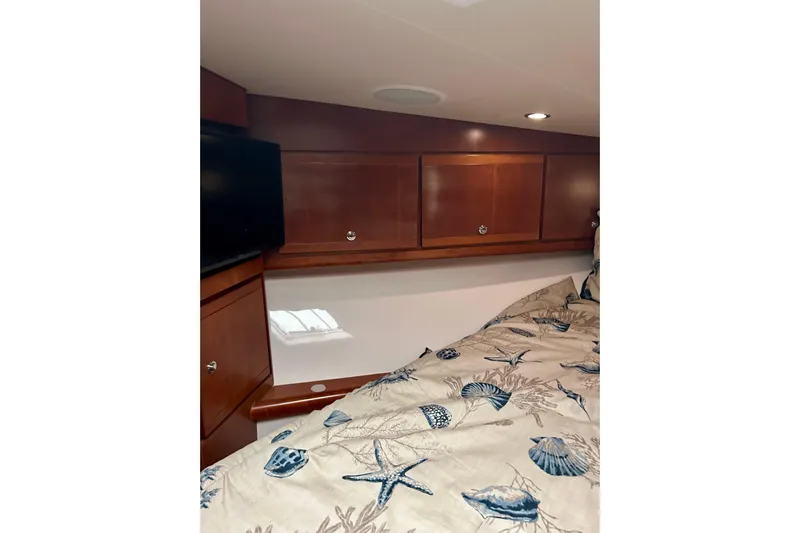  Yacht Photos Pics Cozy cabin interior of 2005 Bertram 390 Convertible with wooden cabinets and patterned bedding.