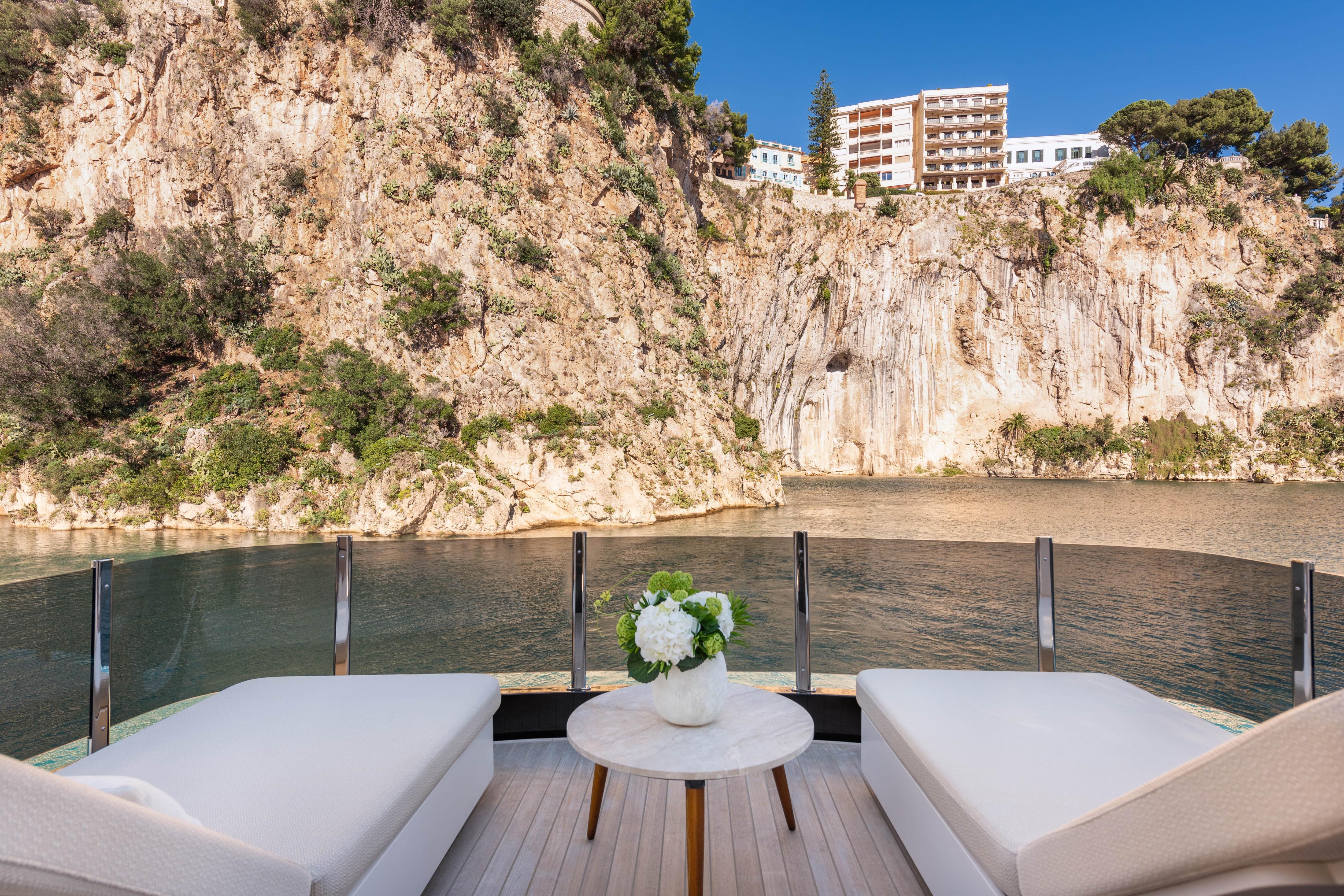 Luxury yacht Explorer 62 (2025) with scenic cliffside view and elegant deck seating.