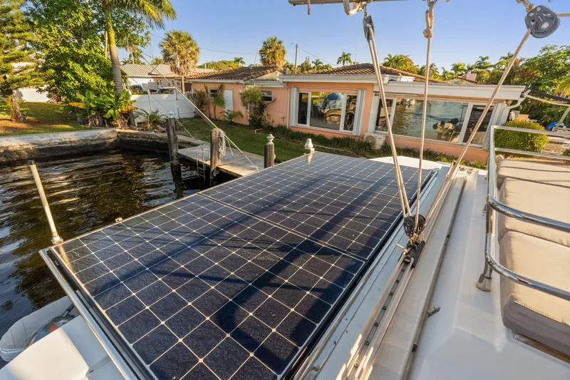 Grand Crew Yacht Photos Pics 2019 Fountaine Pajot 47 catamaran with solar panels docked near a waterfront home.